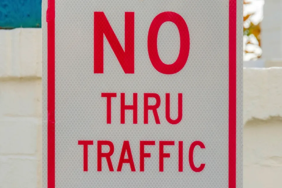 Close-up of white sign with red letters "NO THRU TRAFFIC"